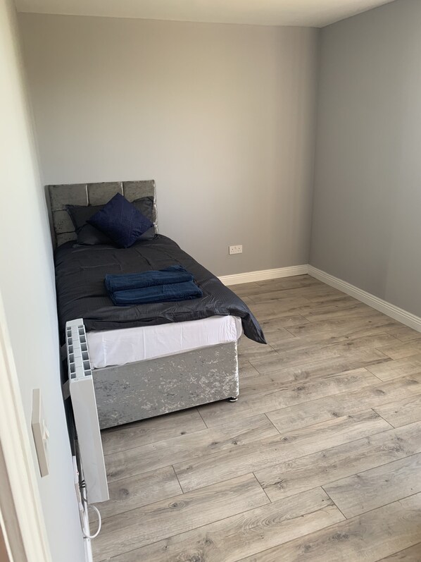 A bedroom with a bed, a radiator, and wooden flooring. - Private Central Apartment Near Kilcullen (Calverstown)