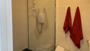 A shower with a glass door, a control panel, and a red towel rack with towels. - Private Central Apartment Near Kilcullen (Calverstown)