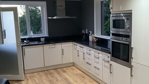 A modern kitchen with white cabinets, a black countertop, and a built-in microwave. - Private Central Apartment Near Kilcullen (Calverstown)
