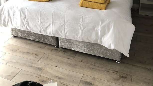 A neatly made bed with a grey headboard, white bedding, and two yellow towels. - Private Central Apartment Near Kilcullen (Calverstown)
