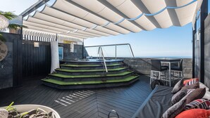 Una terraza en la azotea con zona de estar, una piscina pequeña y vista al océano.