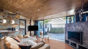 Una sala de estar moderna con una pared de piedra, una chimenea, un sofá y un televisor.