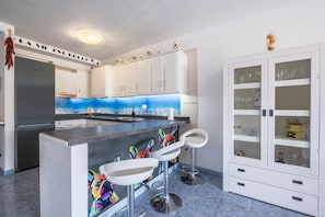 A modern kitchen with a central island, white cabinets, and a decorative backsplash.