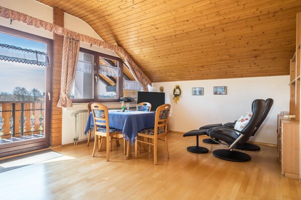 A dining area with a table, chairs, and a massage chair.