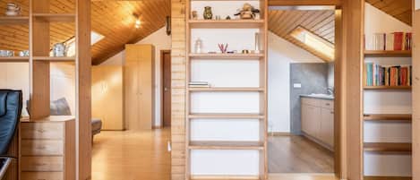 Ein geräumiges Loft mit Holzbalken, einer Erker Ebene mit Bücherregalen und einer Küchenzeile.