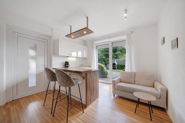 A modern kitchen with a bar area, a sofa, and a small table.