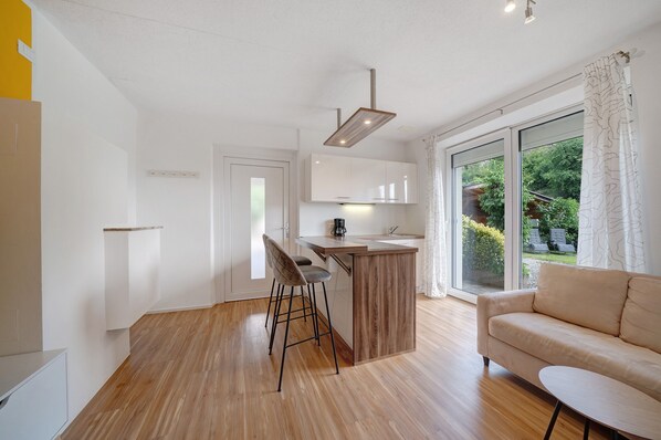 A modern kitchen with a bar area, a sofa, and a dining table. - Holiday Apartment "Mayenburg" with Mountain View, Shared Garden and Pool (Lana/Völlan (BZ) Italien)