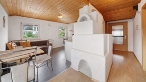 Une cuisine moderne avec un plafond en bois, un coin repas avec une table et des chaises, et une cheminée blanche.