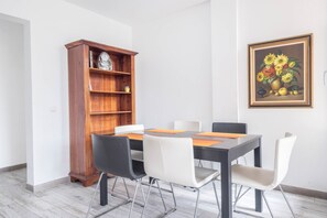 Un coin repas comprenant un buffet en bois, un tableau encadré et une table avec des chaises.
