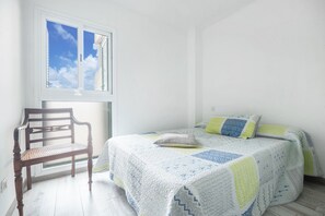 Une chambre à coucher avec un lit, une chaise, une fenêtre et une vue sur le ciel.
