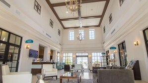 A spacious lobby with a high ceiling, chandeliers, and a mix of seating areas including sofas and chairs.