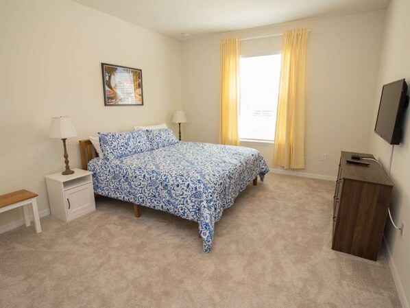 A bedroom with a bed, bedside tables, a nightstand, a dresser, a TV, and a window with curtains. - 9BR | Large Pool Home | Clubhouse | Gated (Kissimmee)
