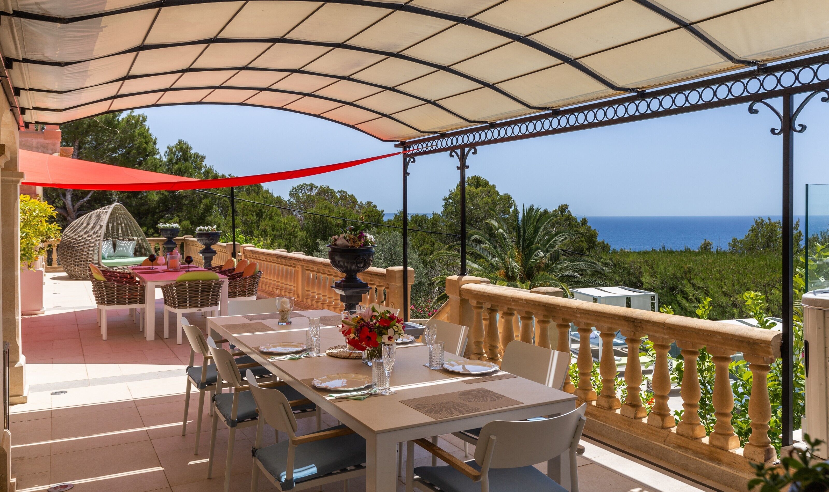 A covered outdoor dining area with tables and chairs, overlooking a scenic view of the sea.