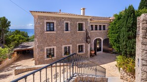 Un edificio de piedra con una escalera, un espacio exterior cubierto y vista al mar.