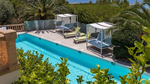 Una piscina con agua azul cristalina, rodeada de vegetación y vistas al mar.