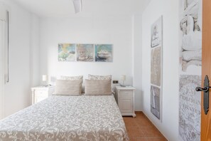 A bedroom with a bed, two bedside tables, a nightstand, and wall art.
