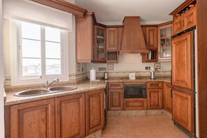 A kitchen with wooden cabinets, a double sink, a built-in oven, and a window with a view.