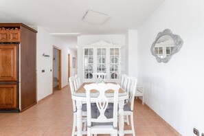 A dining area with a white table and chairs, a cabinet, and a mirror on the wall.