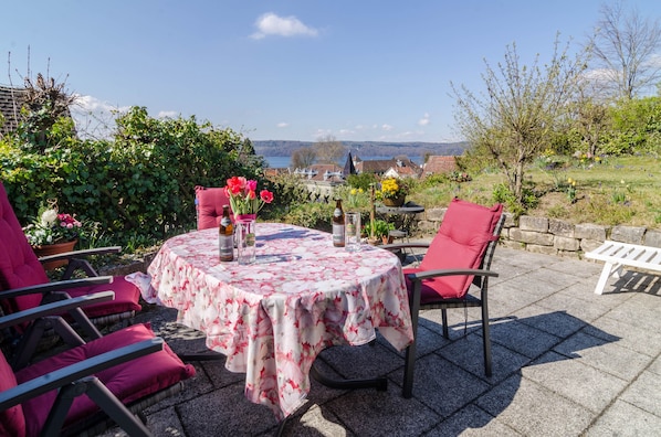 A patio with a round table, chairs, and potted plants.