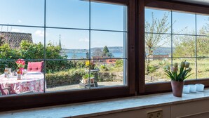 A room with large windows, a table with chairs, and a potted plant. - Holiday Apartment "Munding" with Garden, Terrace, Lake View, Grill & SAT-TV (Überlingen)
