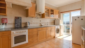 A kitchen with wooden cabinets, a built-in oven, a washing machine, and a large window. - Pet-Friendly Apartment Your Secret in Lagos (Lagos)