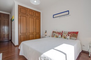 A bedroom with a large bed, wooden wardrobe, and a wall-mounted sign.