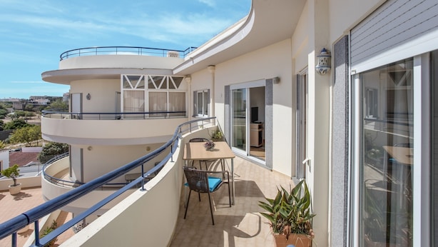 A multi-level balcony with a table and chairs, potted plants, and a view of the surrounding area. - Pet-Friendly Apartment Your Secret in Lagos (Lagos)