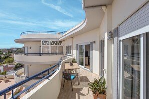 A multi-level balcony with a table and chairs, potted plants, and a view of the surrounding area.