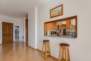 A kitchen with wooden cabinets, a countertop, and two stools.