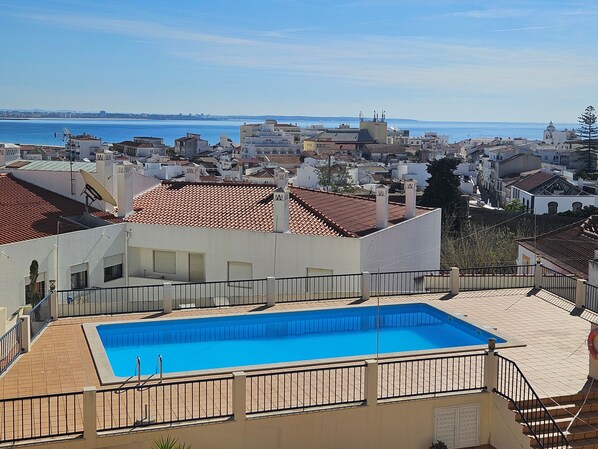 A rooftop swimming pool with a view of the sea and a coastal town.