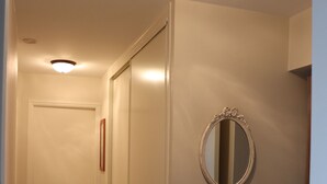 A narrow hallway with a door at the end, a round mirror on the wall, and a light fixture on the ceiling. - L'havre zen cancalais - Apart peaceful 4 pers tt confort (Cancale)