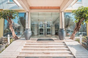 A hotel entrance with a glass door, two large vases, and a stone pathway leading to the door. - Hotel Bulevar Tanjung Duren Jakarta (Jakarta)