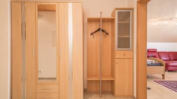 Een kamer met een houten garderobe, een kledingroede en een bed met een rode hoofdeinde.