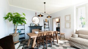 Un comedor con una mesa y sillas de madera, una lámpara colgante y una planta en maceta.