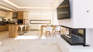 Een moderne keuken met een eethoek, een aan de muur bevestigde televisie en een groot raam.
