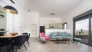 A modern living room with a dining area, a sofa, a coffee table, and a large window with a view.