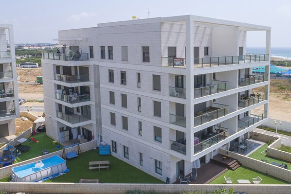 A multi-story hotel with balconies, a swimming pool, and a view of the beach.