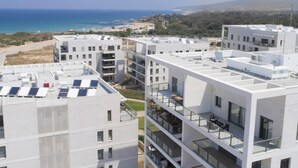 Un immeuble d’appartements moderne, doté de plusieurs étages, de grandes fenêtres et de panneaux solaires sur les toits.