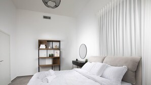 Une chambre moderne avec un grand lit, une table de chevet dotée d’un miroir et une bibliothèque intégrée.