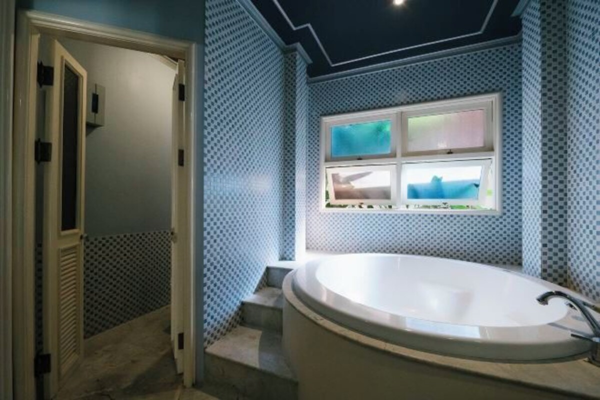 Un baño con una bañera independiente, una ventana con vistas y una pared con diseño.