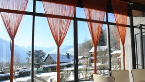 A room with large windows, a table, and chairs. - House with large, quiet garden and beautiful mountain views (ANTIGNAC)