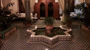 A courtyard with a fountain, tiled floor, and potted plants. - Riad Vega. A haven of peace in the heart of the medina (Fès)