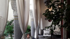 A cozy lounge area with patterned tiles, a sofa, a table, and potted plants. - Riad Vega. A haven of peace in the heart of the medina (Fès)