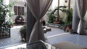 A courtyard with patterned tiles, potted plants, and a seating area. - Riad Vega. A haven of peace in the heart of the medina (Fès)