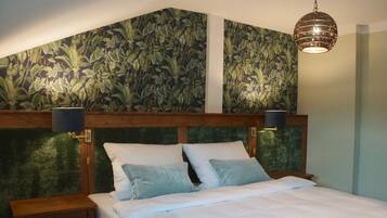 A bedroom with a wooden headboard, a bed with white bedding, two pillows, and a hanging light fixture.