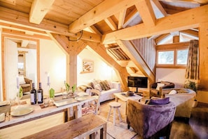 Un interior de madera con comedor, sofá y televisor.