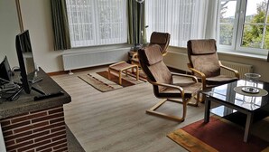 Ein Wohnzimmer mit zwei braunen Ledersesseln, einem Glastisch, einem Fernseher und einem Kamin.