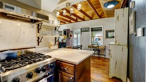 A kitchen with a large island, wooden beams, and a gas stove.