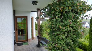 A covered porch with a wooden bench, a glass door, and a wall-mounted light fixture. - Ferienwohnung Dunja (Winterberg)