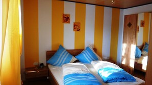 A room with a bed, two pillows, a nightstand, a lamp, and a mirror. - Ferienwohnung Dunja (Winterberg)